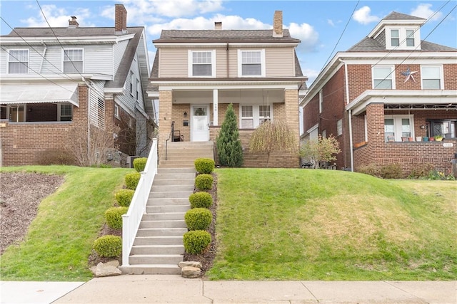 view of front facade with brick siding, stairway, and a front yard