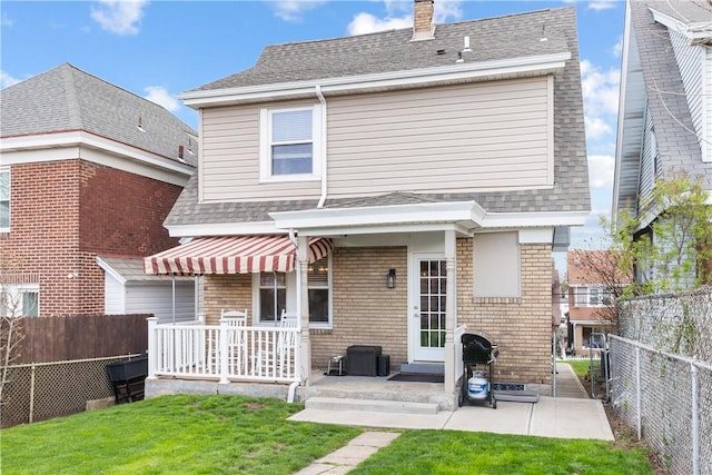rear view of house with a yard, a patio, a shingled roof, and a fenced backyard