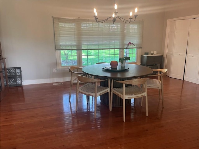 dining area featuring baseboards, visible vents, wood finished floors, and a notable chandelier