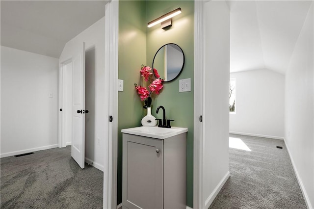 hallway with baseboards, vaulted ceiling, a sink, and carpet floors