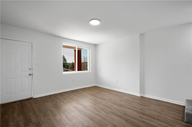 unfurnished room featuring baseboards and dark wood-style flooring