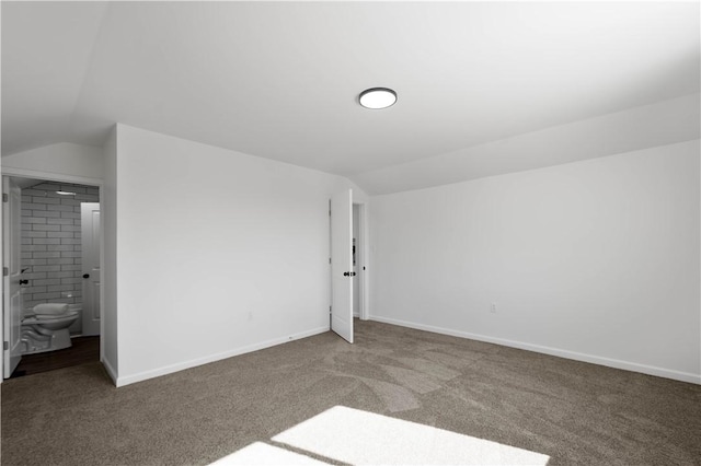 unfurnished bedroom featuring lofted ceiling, baseboards, and carpet