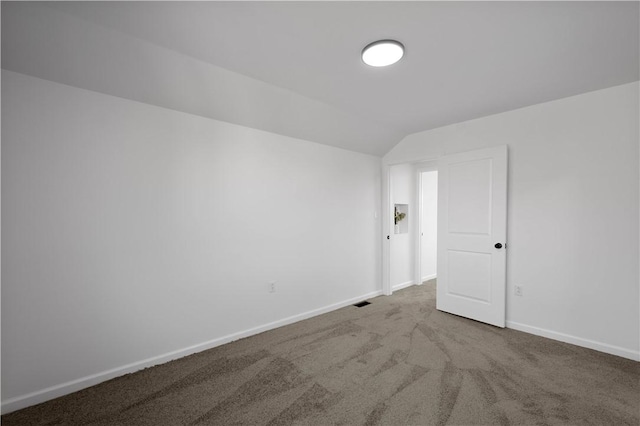 spare room featuring lofted ceiling, carpet floors, and baseboards