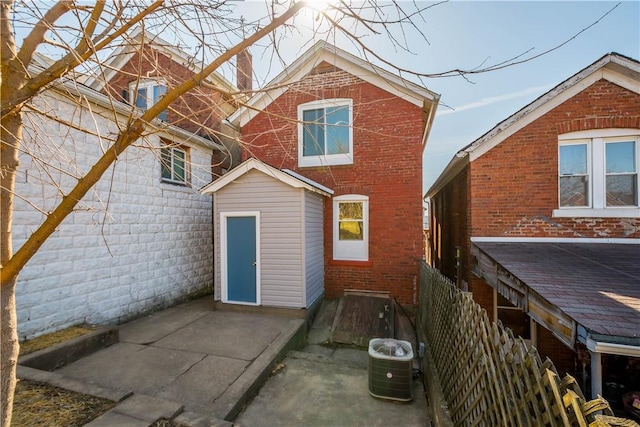 back of house featuring central air condition unit, brick siding, and a patio area