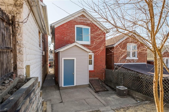 back of house with brick siding and central AC unit