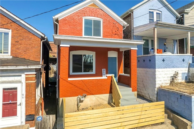 back of house with a porch and brick siding