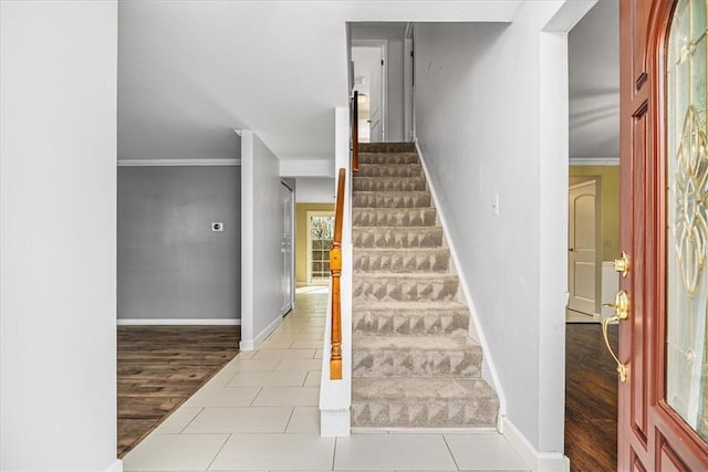 stairway featuring wood finished floors, baseboards, and ornamental molding