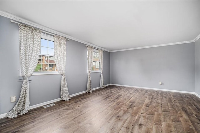 empty room featuring crown molding, baseboards, wood finished floors, and a healthy amount of sunlight