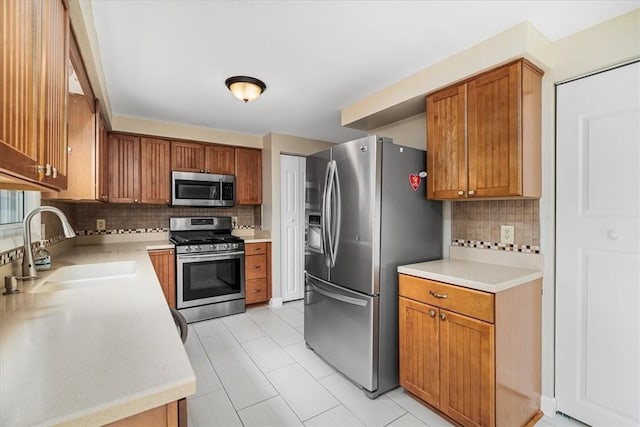 kitchen with stainless steel appliances, light countertops, a sink, and tasteful backsplash