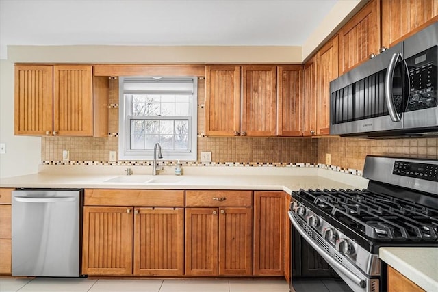 kitchen with backsplash, light countertops, stainless steel appliances, and a sink