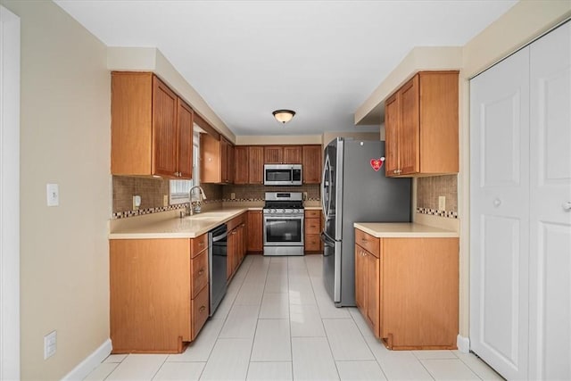 kitchen featuring decorative backsplash, appliances with stainless steel finishes, a sink, and light countertops