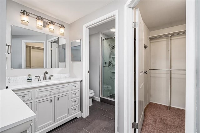 full bath with vanity, a shower stall, a walk in closet, and toilet