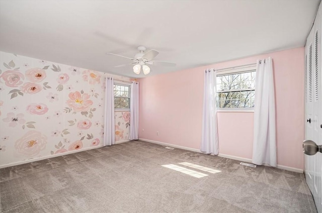 empty room featuring carpet, a ceiling fan, and baseboards