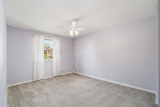 carpeted spare room featuring baseboards and ceiling fan