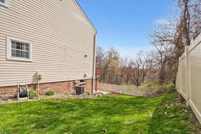 view of side of property featuring a fenced backyard, a yard, and central AC