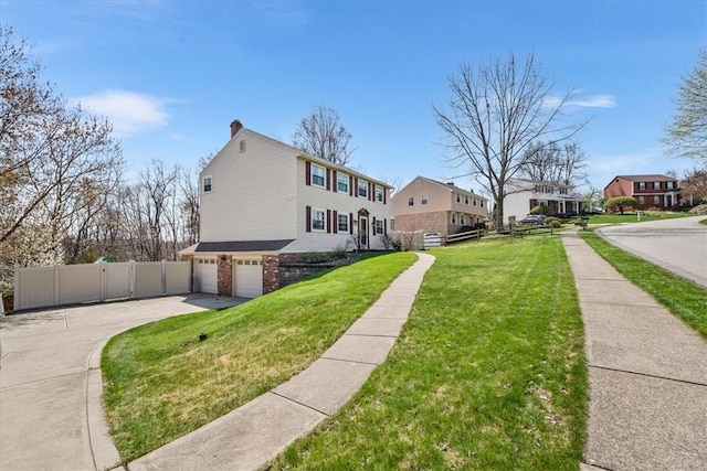 view of front of house with a chimney, fence, an attached garage, driveway, and a front yard
