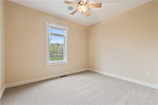 empty room featuring carpet floors, a ceiling fan, visible vents, and baseboards