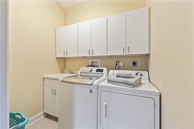 clothes washing area with separate washer and dryer, baseboards, cabinet space, and a sink