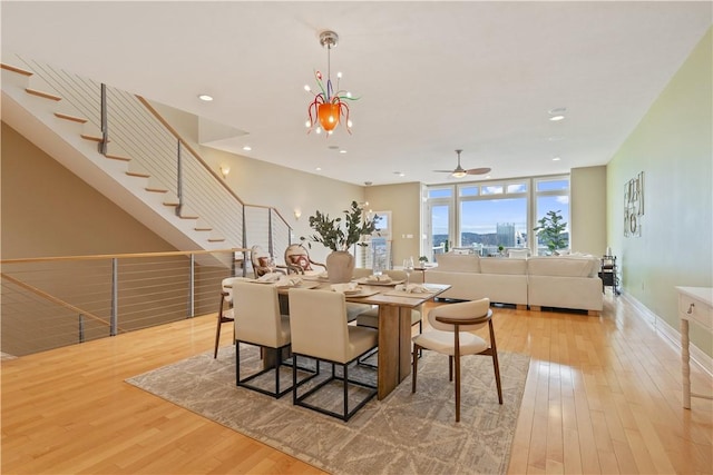 dining space with ceiling fan with notable chandelier, recessed lighting, light wood-style floors, and stairway