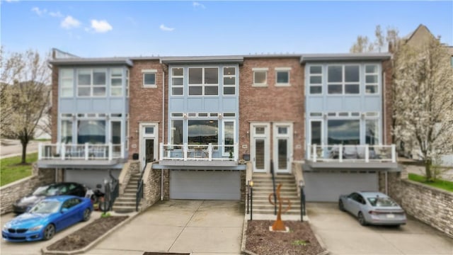 view of front facade featuring concrete driveway, brick siding, stairs, and a garage
