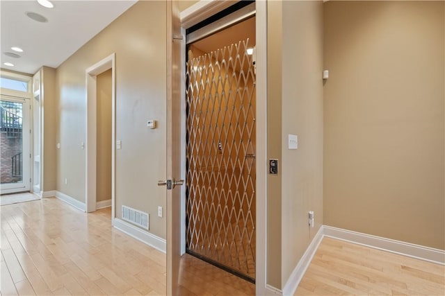 hallway featuring baseboards, light wood finished floors, visible vents, and recessed lighting