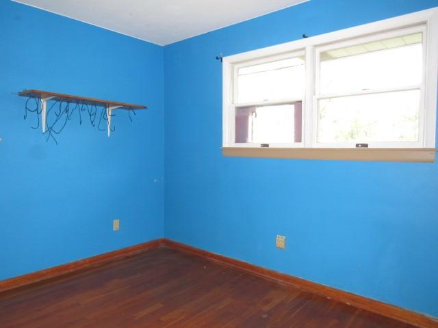 empty room featuring baseboards and dark wood-style flooring