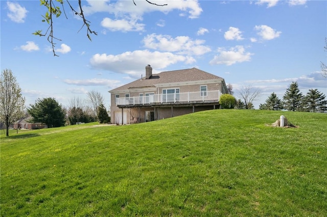 rear view of house featuring a wooden deck, a lawn, and a chimney