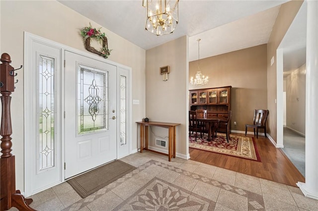 foyer entrance with baseboards, a chandelier, and visible vents