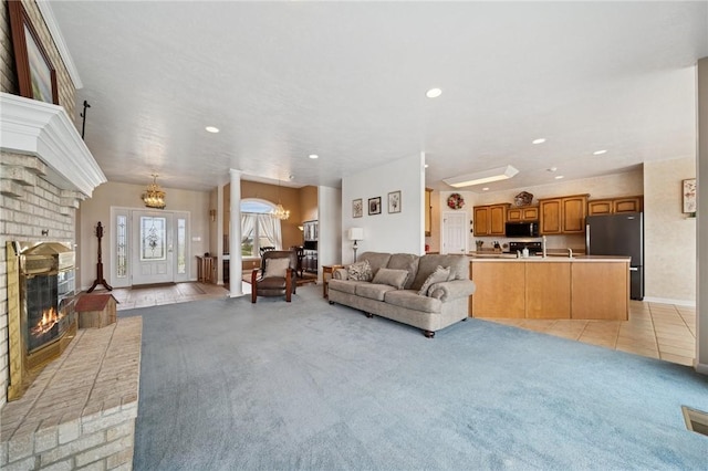 living room with light carpet, baseboards, recessed lighting, a notable chandelier, and a brick fireplace