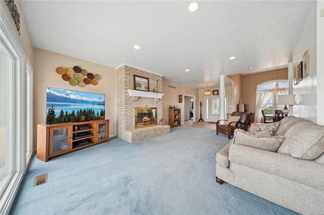 living area with a fireplace, a notable chandelier, visible vents, and carpet