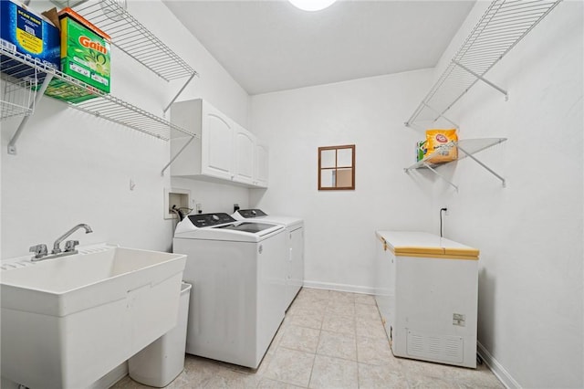 clothes washing area featuring washer and clothes dryer, a sink, baseboards, cabinet space, and light tile patterned floors