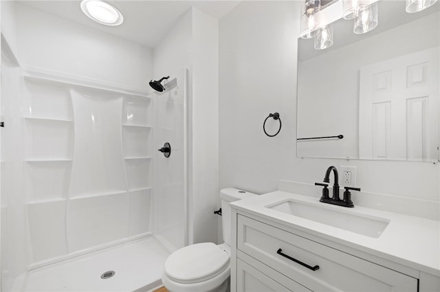 bathroom featuring a shower stall, toilet, and vanity