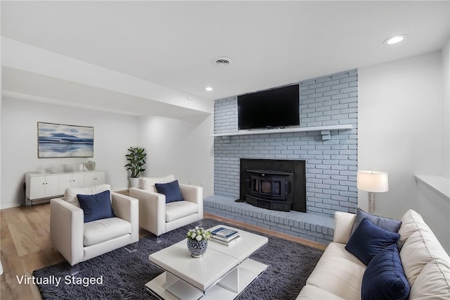 living room featuring a wood stove, recessed lighting, visible vents, baseboards, and wood finished floors