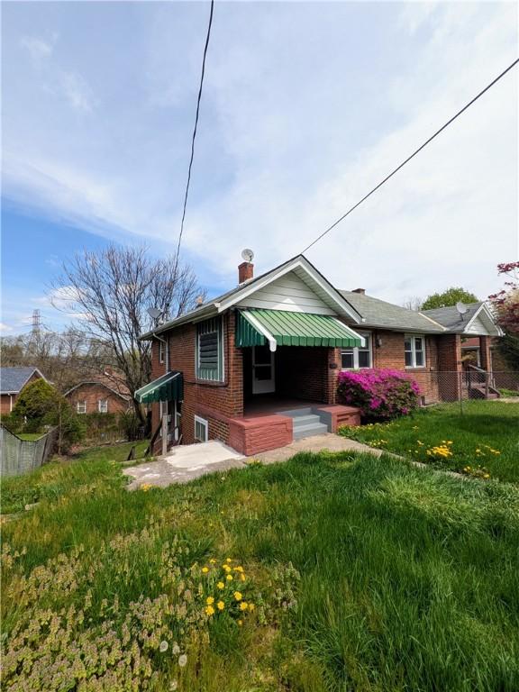 341 Ohio Ave, Clairton, PA 15025 - rear view of house with fence, a lawn, a chimney, and brick siding