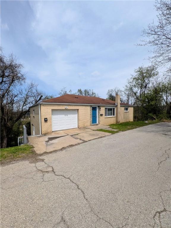 300 Thompson Ave, Clairton, PA 15025 - ranch-style home featuring an attached garage, driveway, brick siding, and a chimney
