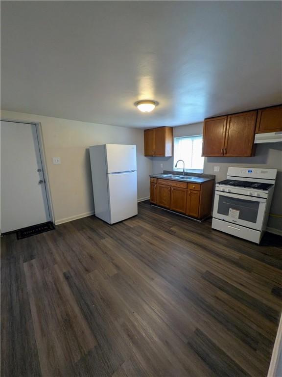 300 Thompson Ave, Clairton, PA 15025 - kitchen with a sink, white appliances, brown cabinetry, under cabinet range hood, and dark wood-type flooring