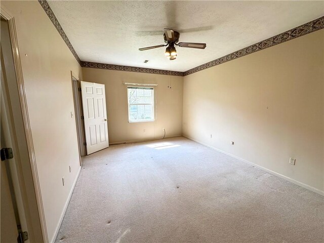 unfurnished room with a textured ceiling, a ceiling fan, carpet, baseboards, and crown molding