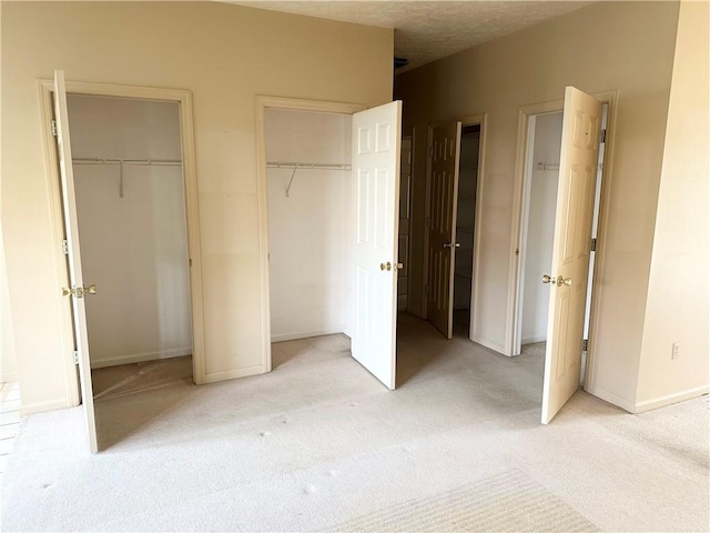 unfurnished bedroom with multiple closets, light colored carpet, and baseboards