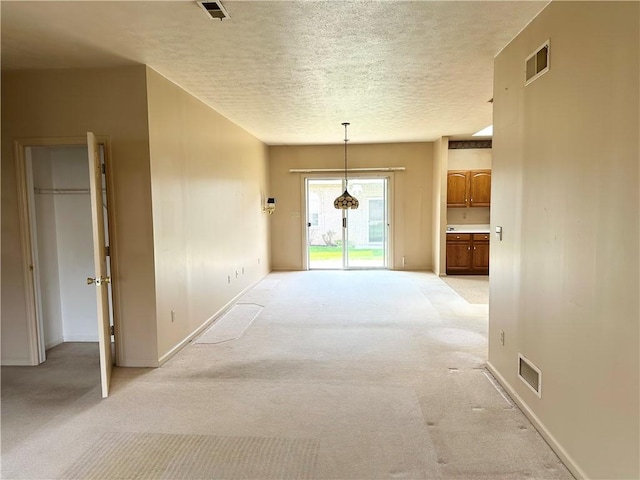unfurnished dining area featuring light colored carpet, a textured ceiling, and baseboards