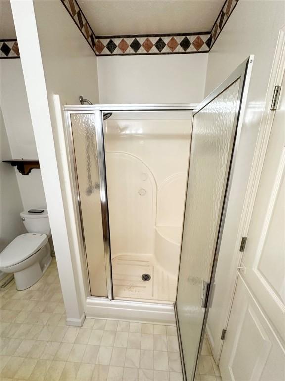 bathroom featuring a stall shower and toilet