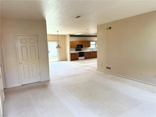 unfurnished living room featuring light carpet, baseboards, plenty of natural light, and a sink