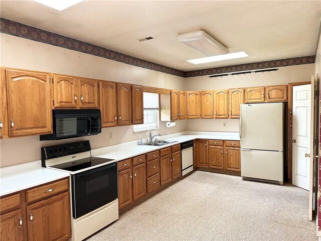 kitchen featuring freestanding refrigerator, black microwave, electric range oven, dishwashing machine, and brown cabinets