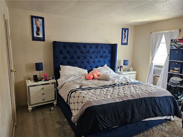 bedroom with wood finished floors, a textured ceiling, cooling unit, and a textured wall