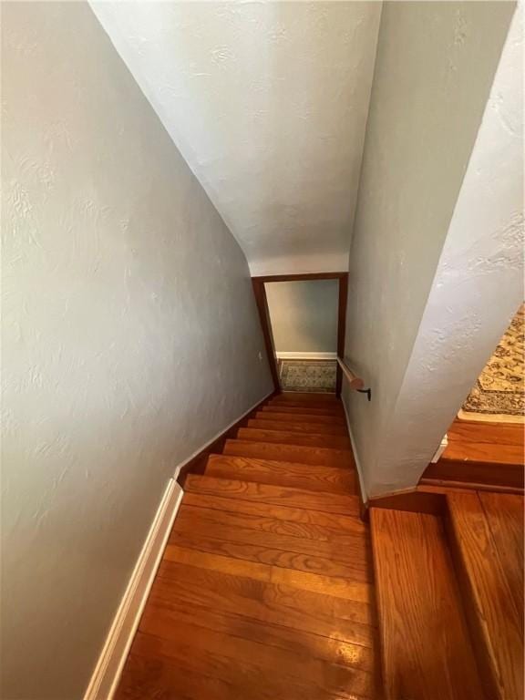 staircase featuring wood finished floors and baseboards