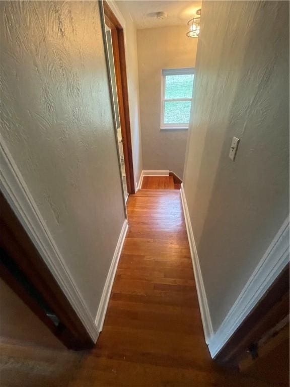 hallway featuring baseboards and wood finished floors
