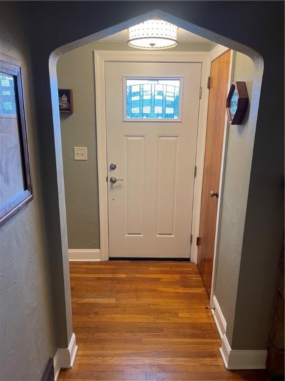 doorway to outside featuring baseboards and wood finished floors
