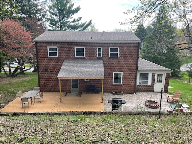 rear view of property with a fire pit, brick siding, and a deck