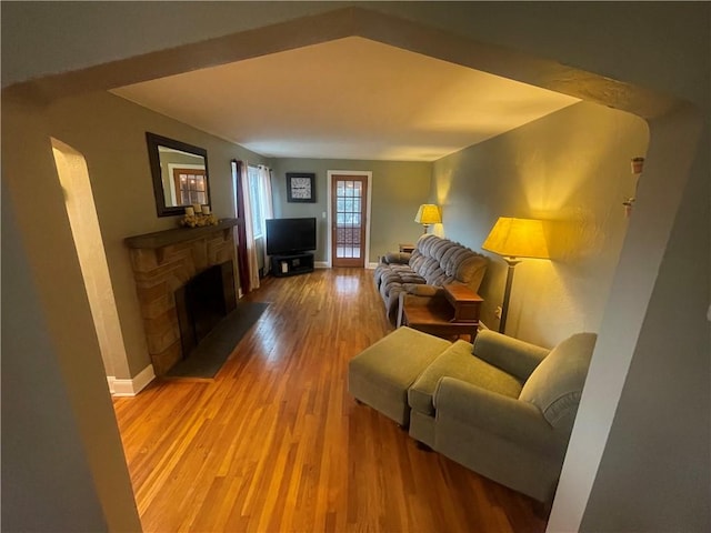 living area featuring light wood finished floors, baseboards, and a fireplace