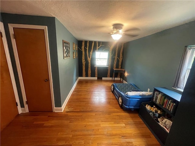 unfurnished bedroom with baseboards, wood finished floors, a textured ceiling, and ceiling fan