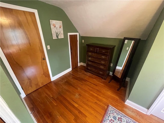 interior space with baseboards, vaulted ceiling, and wood finished floors